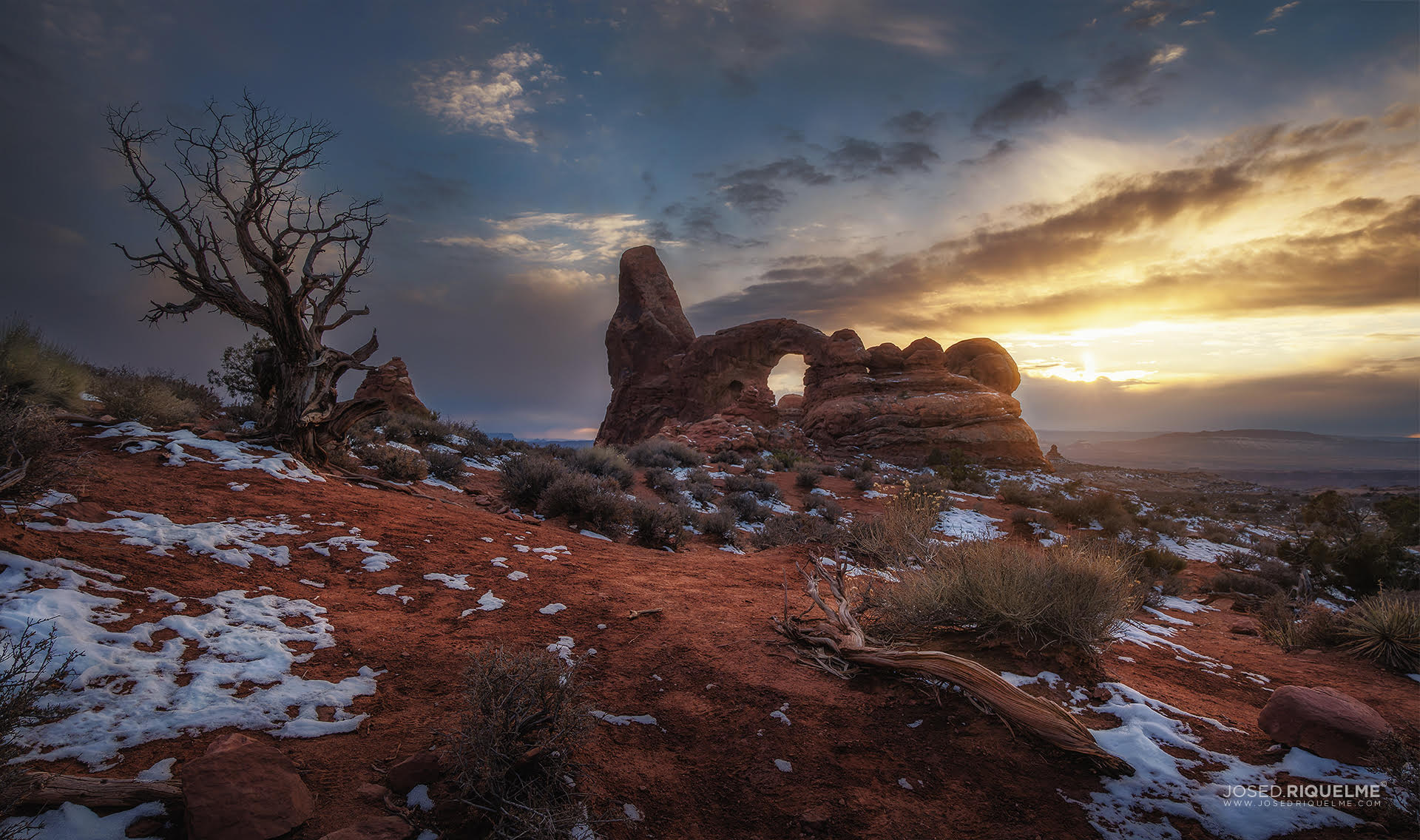 El arco de Turret y un enebro cubiertos de nieve al atardecer, Parque Nacional de Arches, Utah